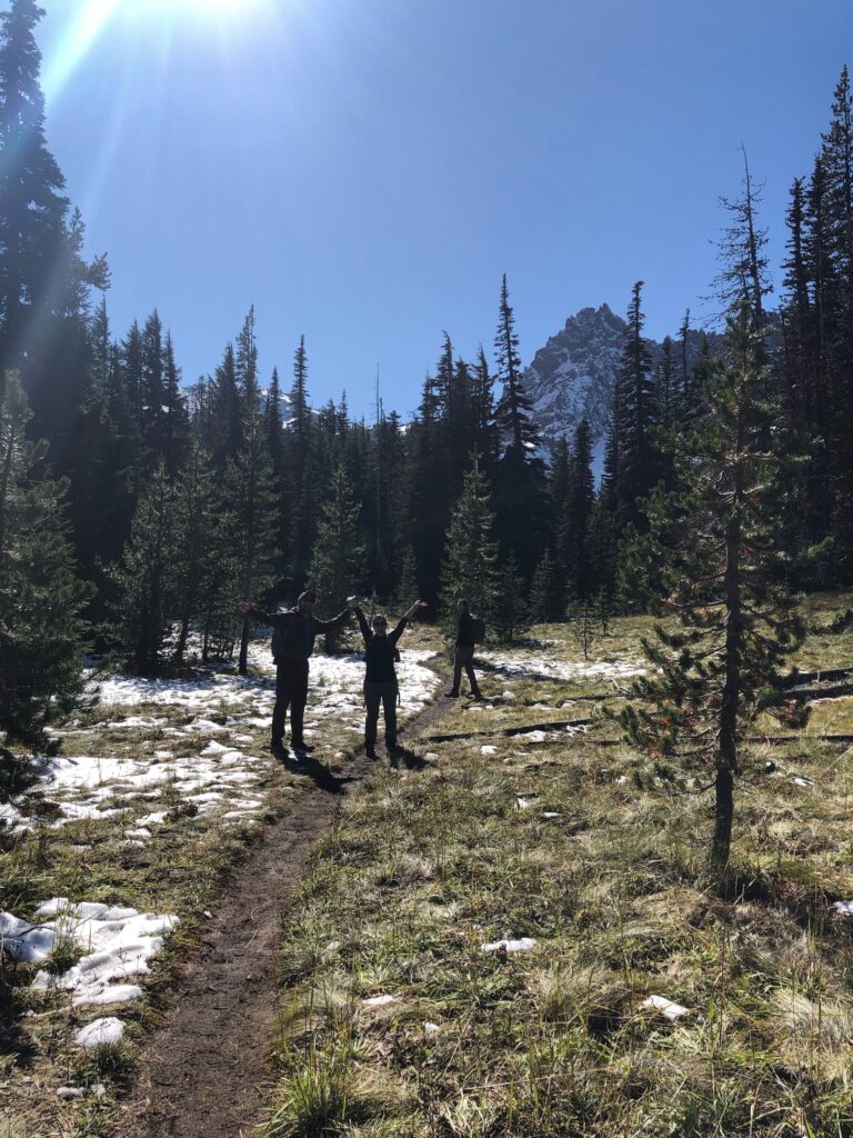 Hikers on a trail in Central Oregon with mixed snow and dry ground, showing typical changing conditions throughout the day.