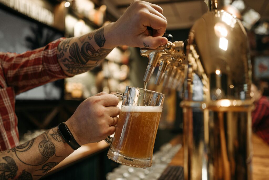 Bartender pouring a craft beer from a tap at a brewery.
