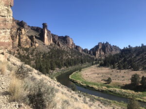 Smith Rock State Park in Central Oregon with the Crooked River and canyon cliffs under a clear blue sky.